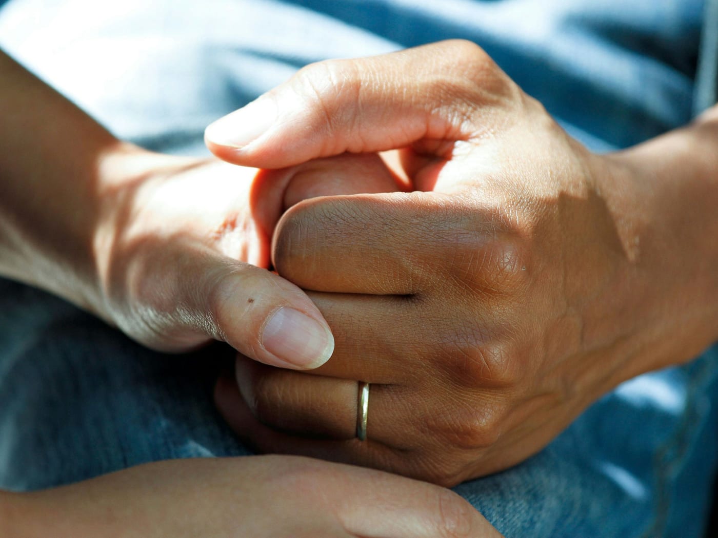 Mãos de uma pessoa idosa seguradas pelas mãos de outra pessoa